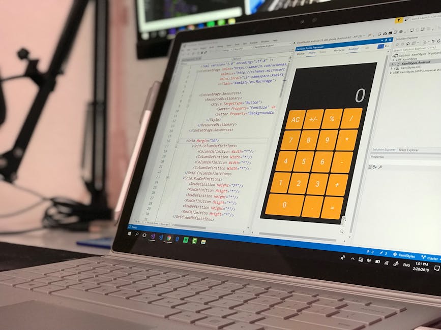A close-up view of a laptop computer displaying a coding editor with HTML and CSS code on the left side of the screen. On the right side, there is a large, visually distinctive orange calculator inter